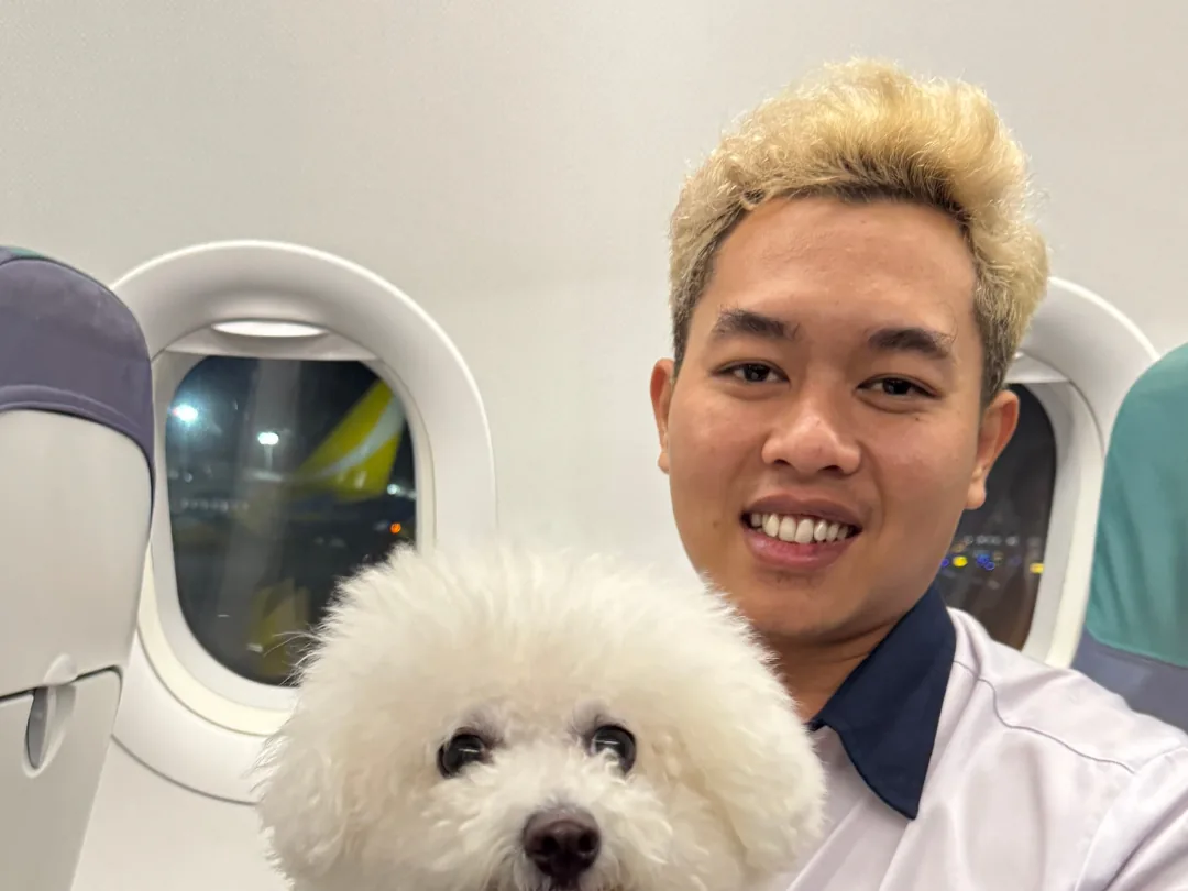 Escort seated with a Bichon Frise at the cabin window