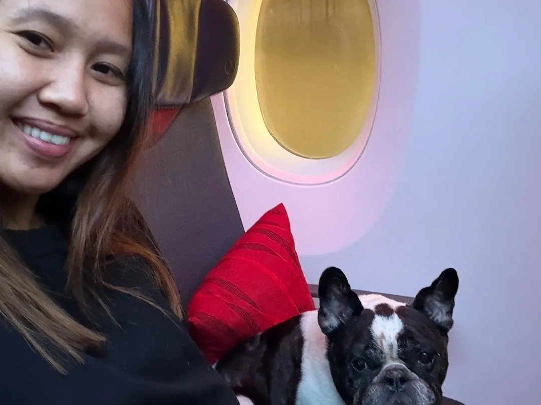 Escort seated beside a French Bulldog at the cabin window