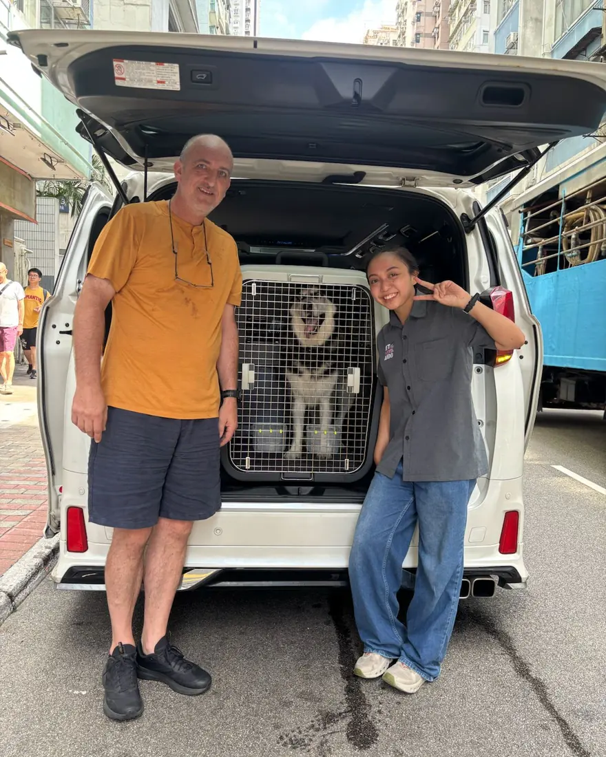 Escort and owner beside a van with a travel crate loaded in the back