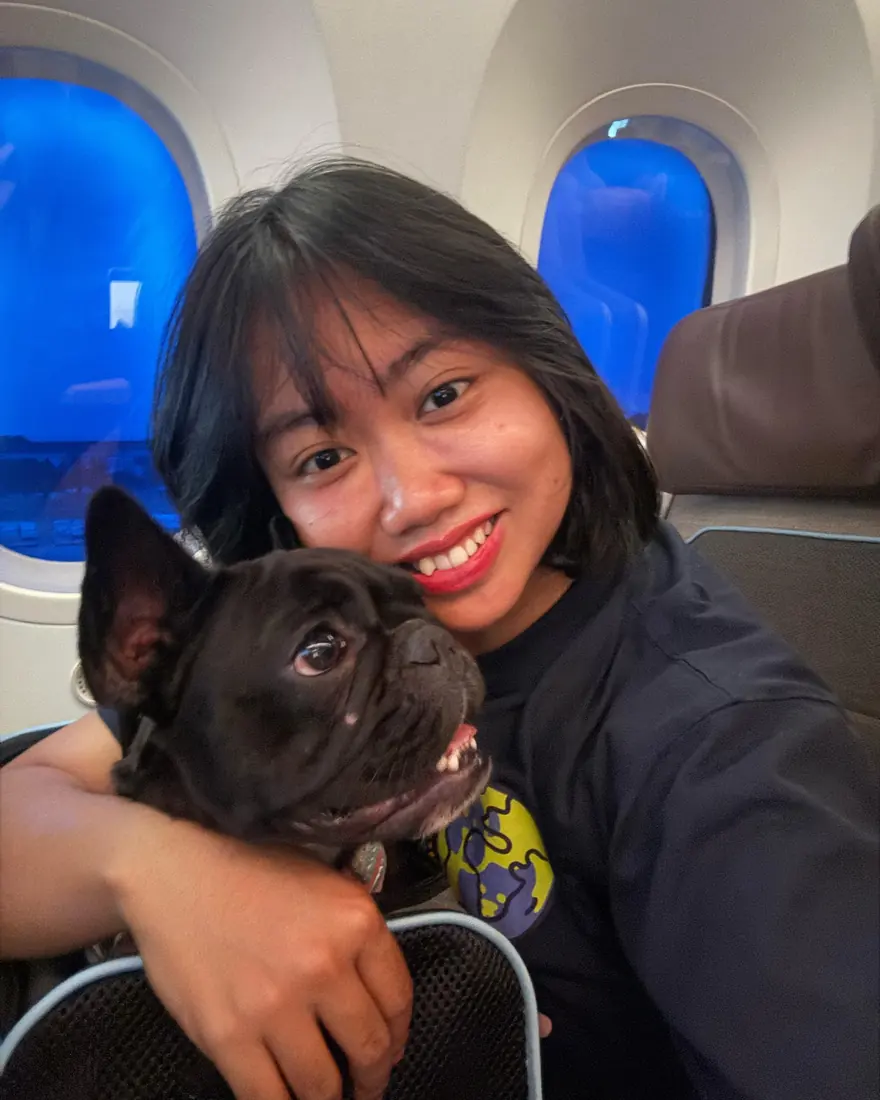 Escort hugging a black French Bulldog in the aircraft cabin